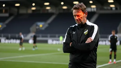 A 35-year-old Häcken coach in a black and white striped training top, his weathered face set in a mix of frustration and...