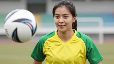 A close-up shot of a young, athletic-looking woman with a determined expression, wearing a bright green and yellow...