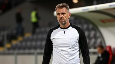 A 35-year-old Häcken assistant coach, wearing a black and white plain cotton training top with a fitted silhouette...