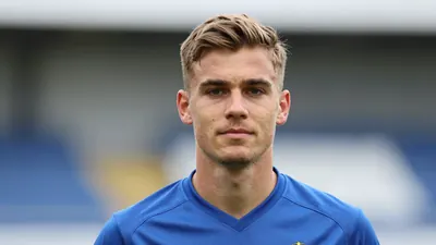A young male midfielder, mid-20s, wearing a solid blue Häcken kit, head-and-shoulders portrait, background blurred