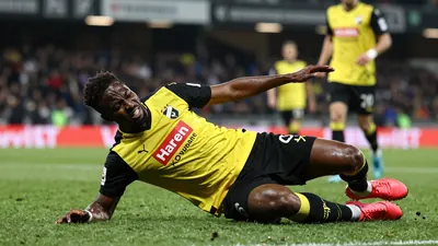 A photo of Axel Kouamé, Häcken player, falling to the ground after a collision with an opponent, with a look of pain on...