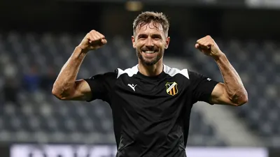 A 35-year-old, 5'10" Häcken midfielder with a rugged build, dressed in a plain black and white polyester training top...